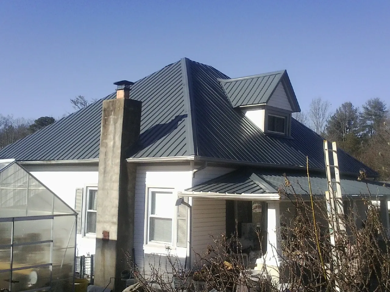Dark blue standing seam metal roof on a white farmhouse with dormer — Slate & Tile Roof Repair by Roofing Brothers in Avon By The Sea