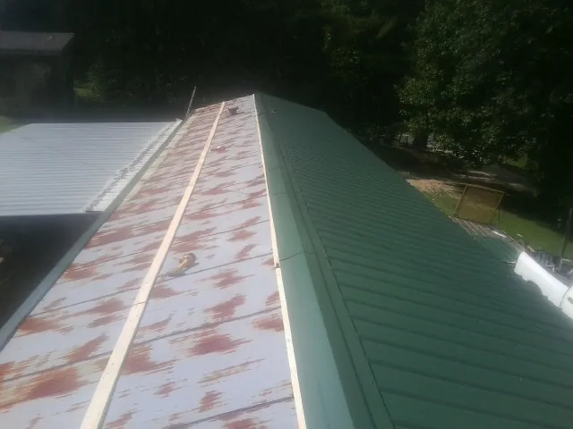 Old rusted panels beside newly installed green metal roofing — Wind Damage Roof Repair by Roofing Brothers in Avon By The Sea