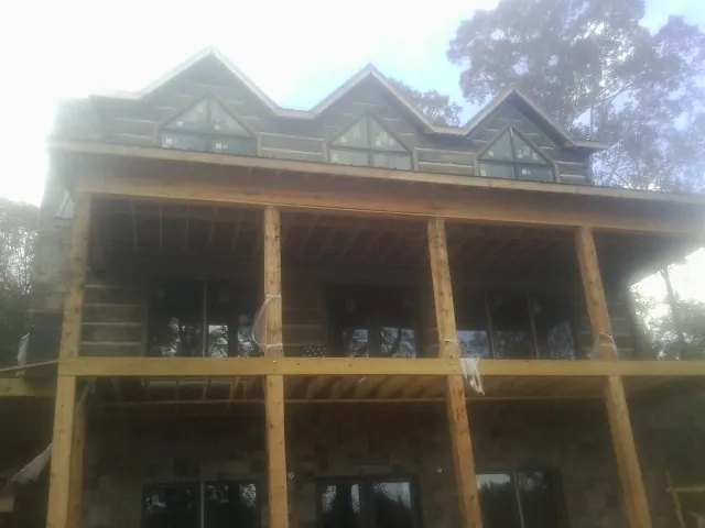 Dormers and porch framing on a large log home under construction — Roof Coating work by our crew in Avon By The Sea