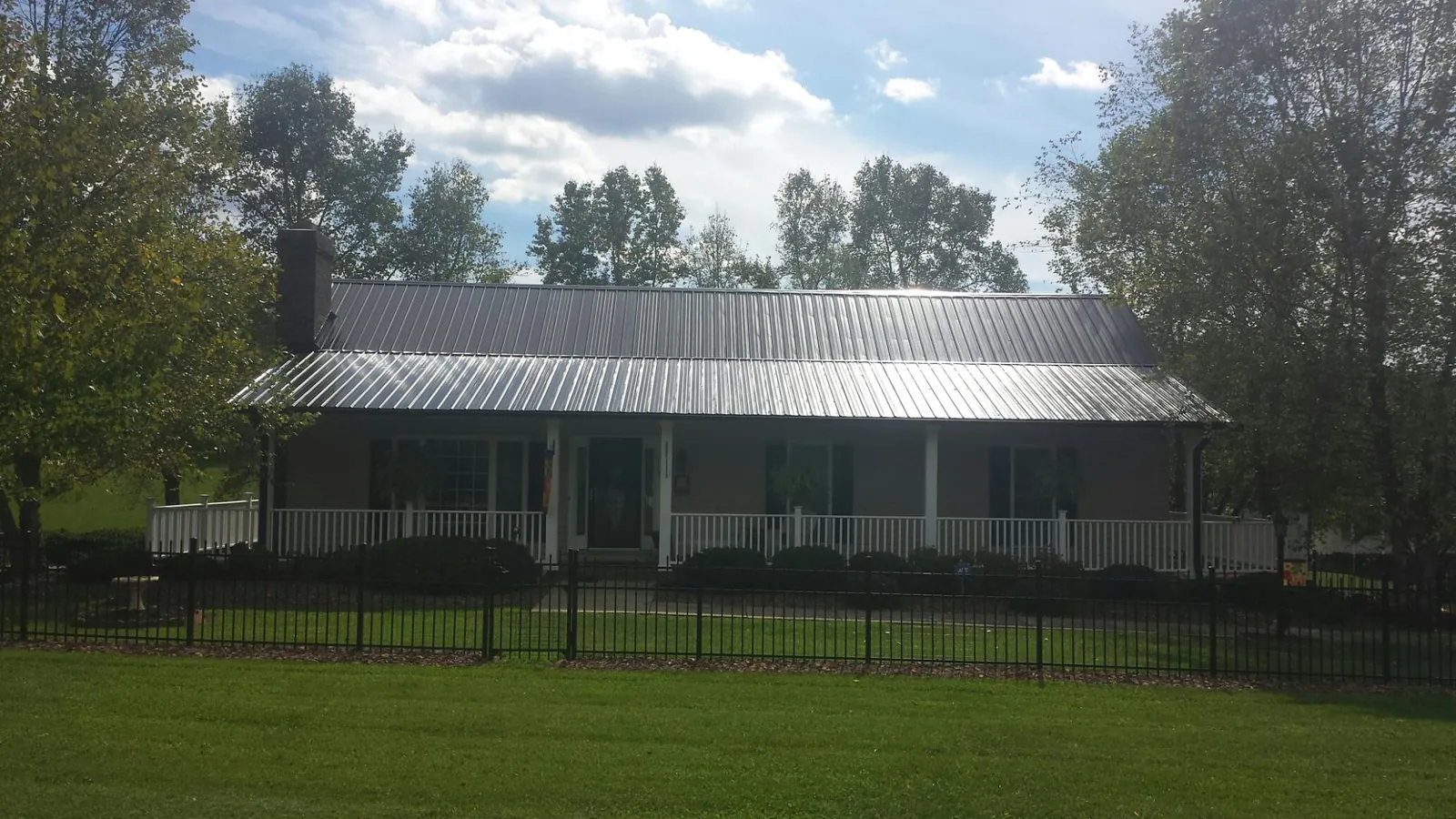 Gray metal roof on a brick ranch with a full width front porch — Gutter Guard Installation work by our crew in Avon By The Sea