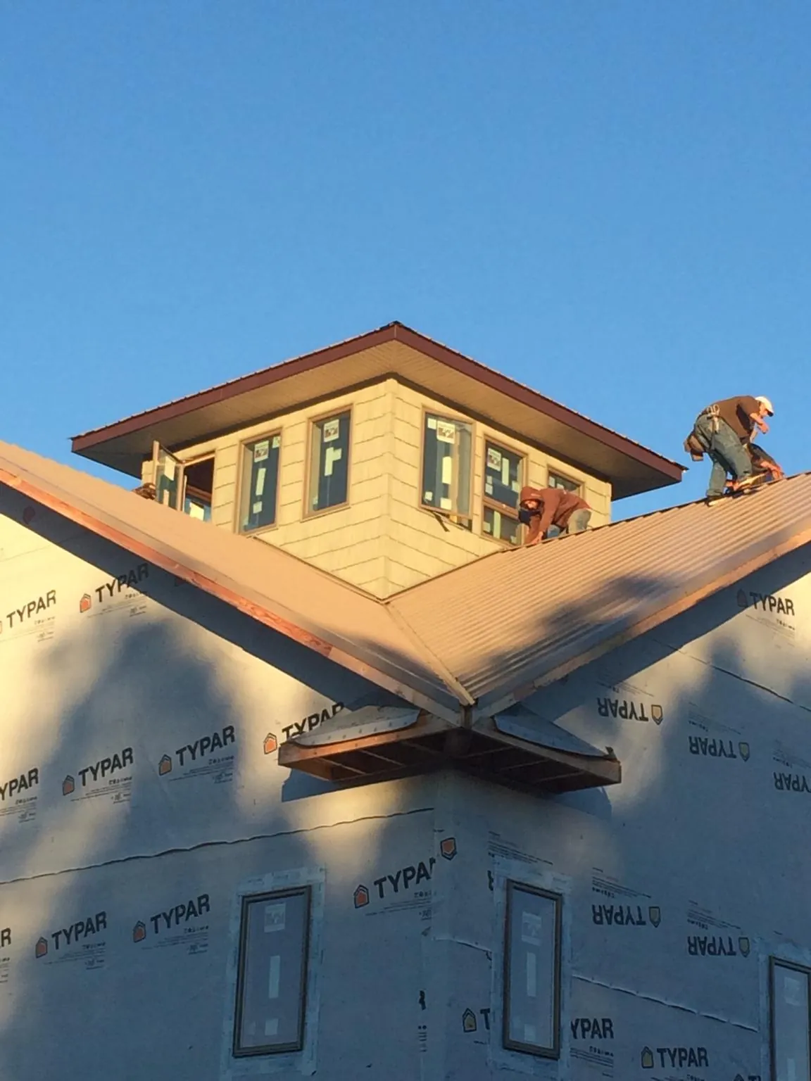 Roofers working around a rooftop cupola on a new metal roof at sunset — Roof Waterproofing in Avon By The Sea by Roofing Brothers